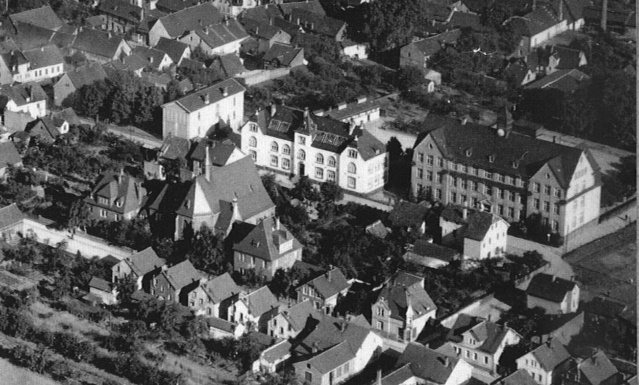Historische Luftaufnahme der Eberstädter Schulinsel: mehrere Schulgebäude nebeneinander, ringsum die Wohnbebauung des Ortes